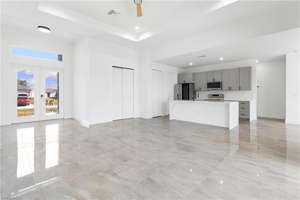 Unfurnished living room with a tray ceiling, baseboards, visible vents, and recessed lighting