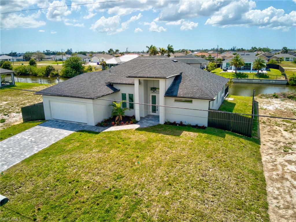 View of front facade featuring an attached garage, fence, a residential view, and decorative driveway