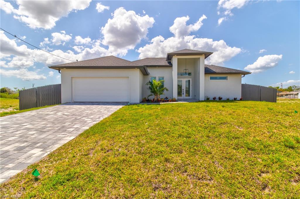 Prairie-style home with stucco siding, decorative driveway, a front yard, french doors, and a garage
