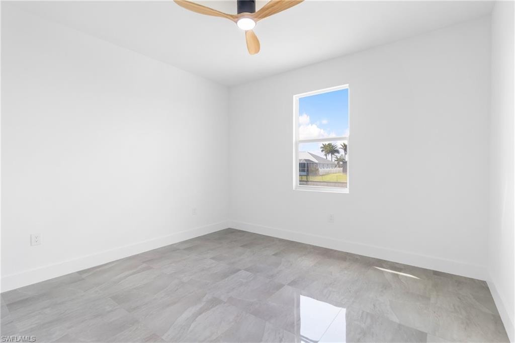 Empty room featuring baseboards and a ceiling fan