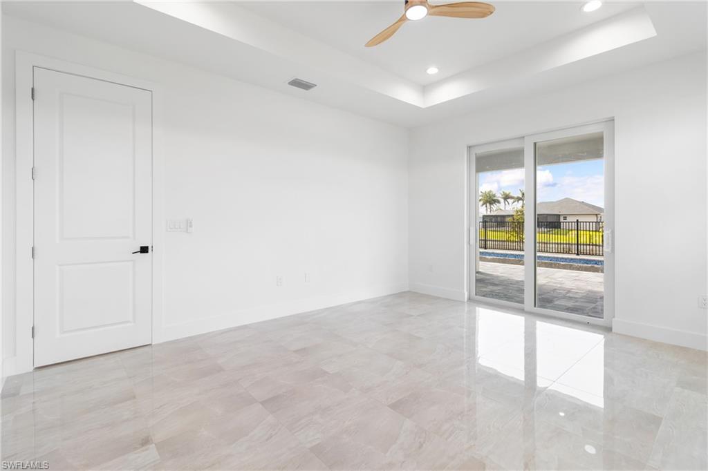 Spare room with visible vents, baseboards, a ceiling fan, a tray ceiling, and recessed lighting