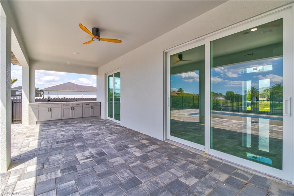 View of patio with a ceiling fan, a sink, fence, and exterior kitchen