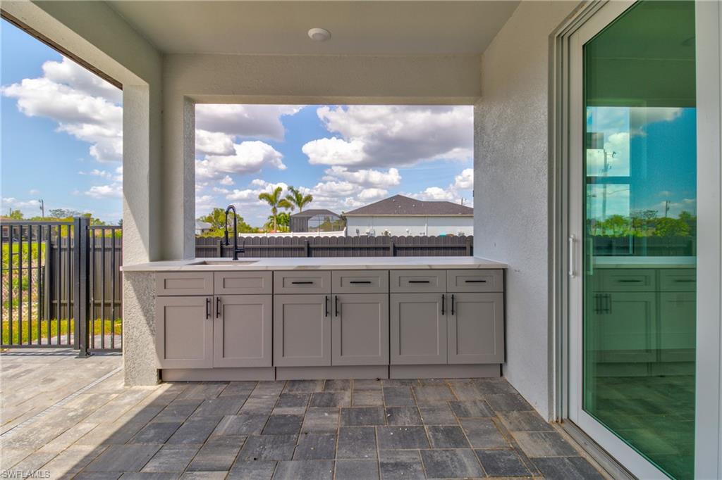 View of patio featuring area for grilling, a sink, and fence