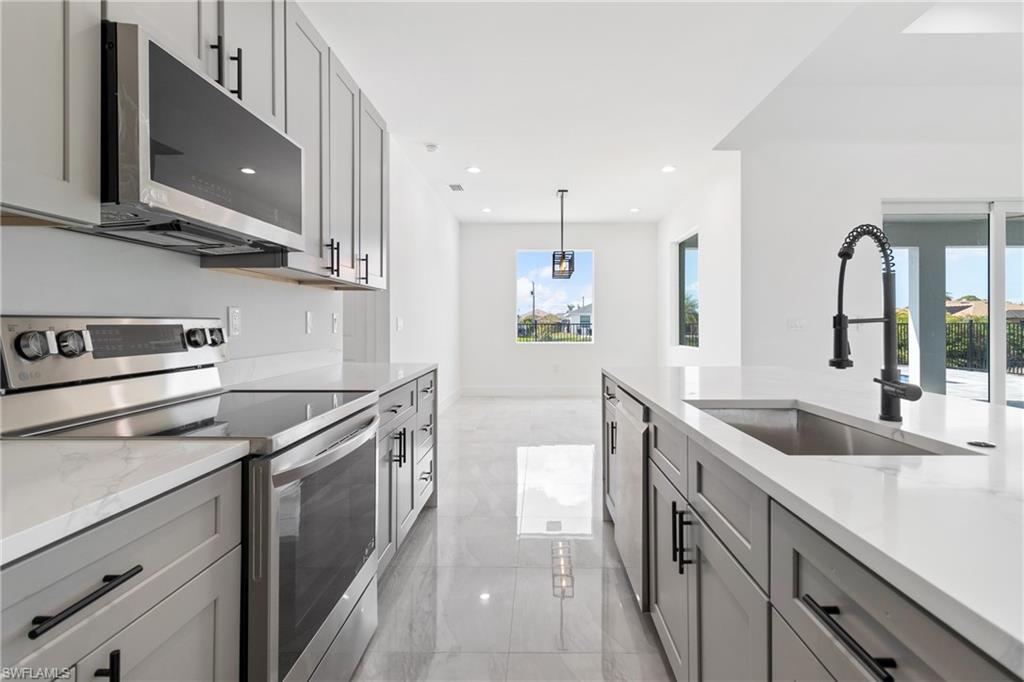 Kitchen featuring gray cabinets, a sink, plenty of natural light, and stainless steel appliances