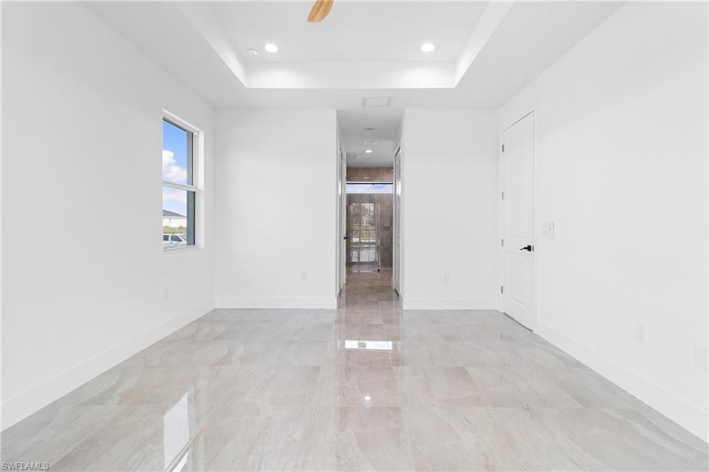 Unfurnished room with a tray ceiling, baseboards, and recessed lighting