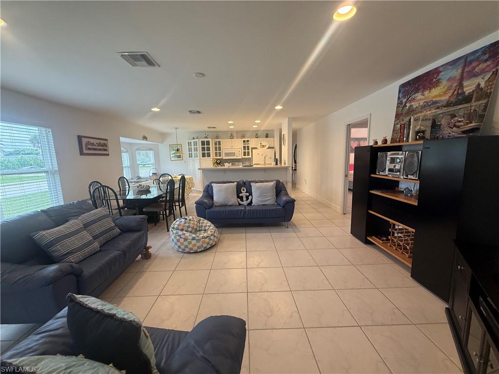 Living room with french doors, light tile patterned flooring, and recessed lighting