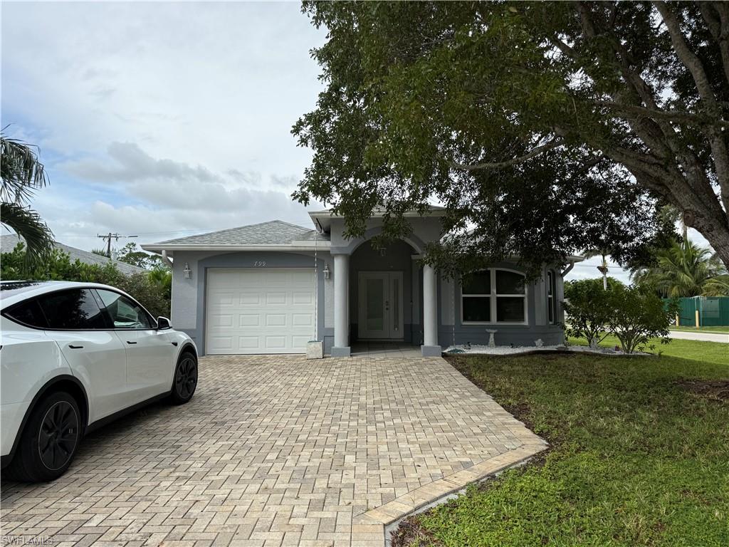 Ranch-style house featuring a garage, a front lawn, decorative driveway, and roof with shingles