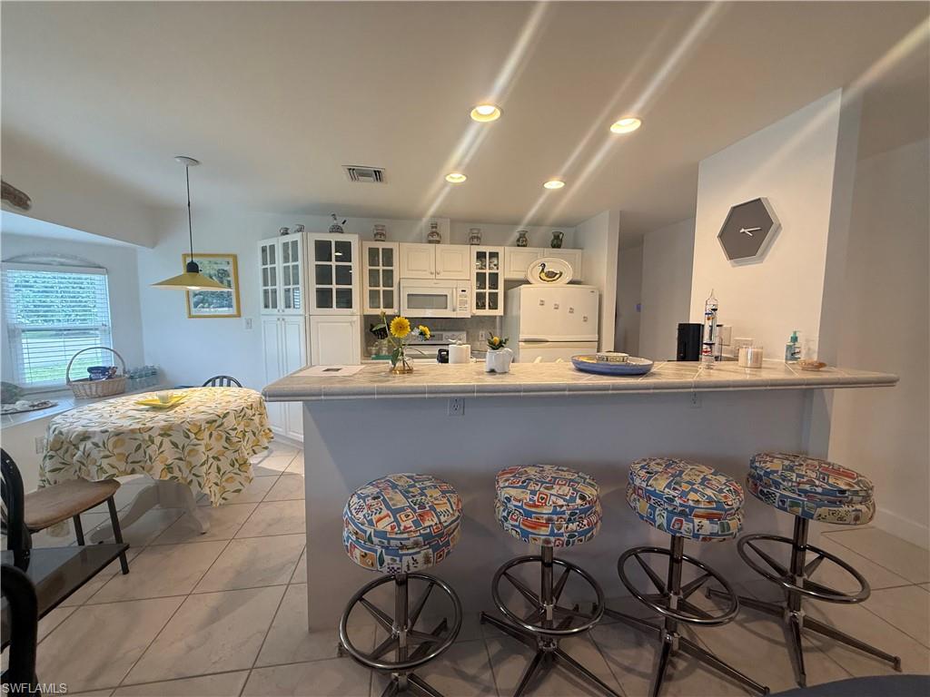 Kitchen featuring white cabinets, tile counters, white appliances, glass insert cabinets, and recessed lighting