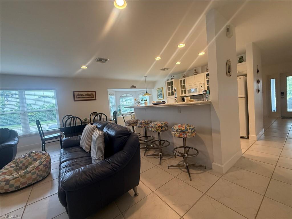 Living room with healthy amount of natural light, recessed lighting, light tile patterned flooring, and french doors