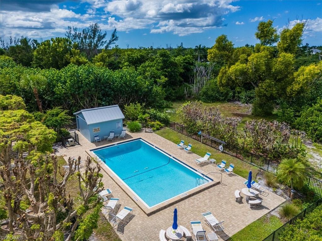 Community pool featuring a patio, an outbuilding, a view of trees, outdoor dining space, and a storage structure