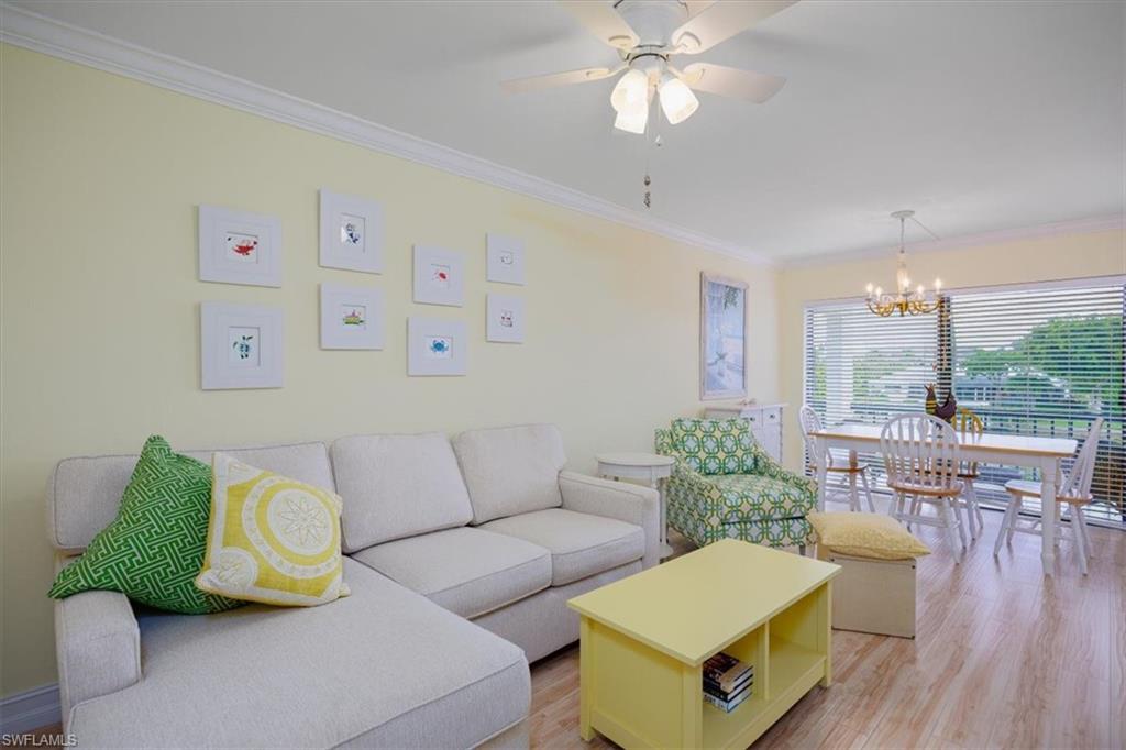 Living area featuring ornamental molding, light wood-style floors, a chandelier, and a ceiling fan