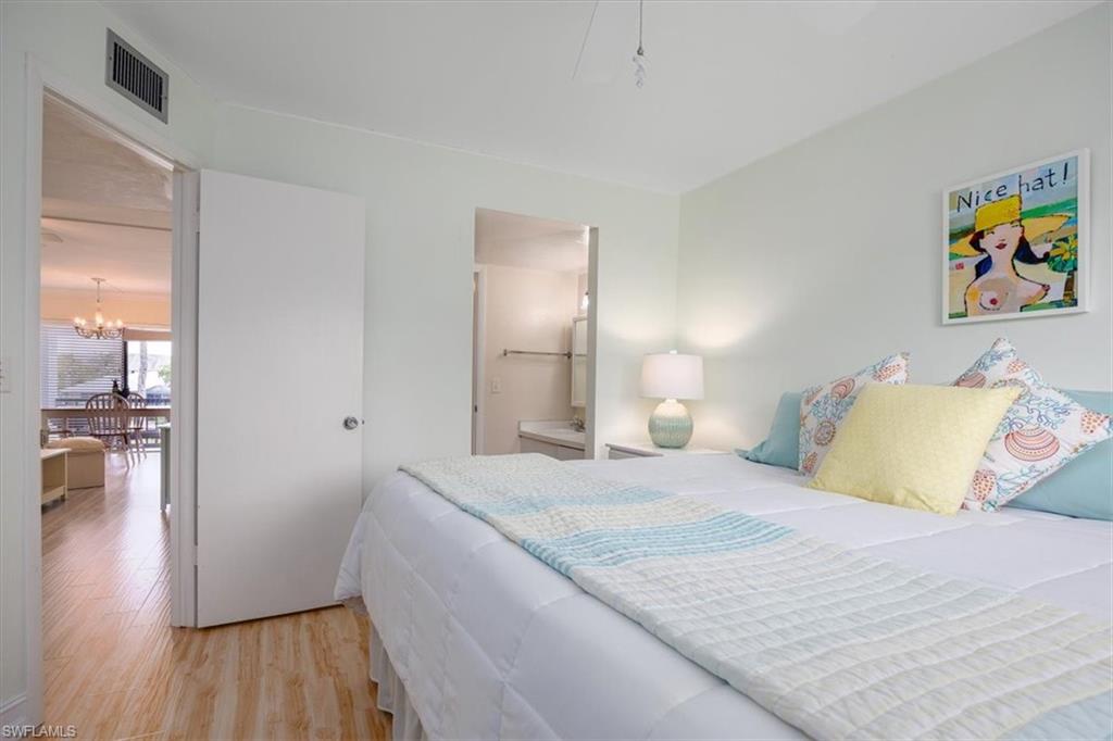 Bedroom featuring light wood-style flooring, a chandelier, and connected bathroom