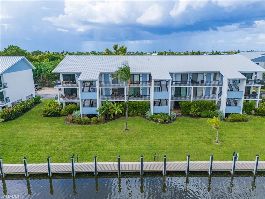 Rear view of house with a water view, a balcony, and a lawn