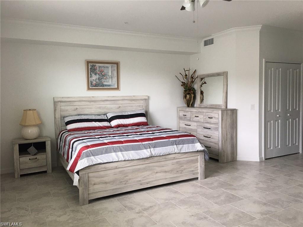 Bedroom with light tile patterned flooring, a closet, ornamental molding, and ceiling fan