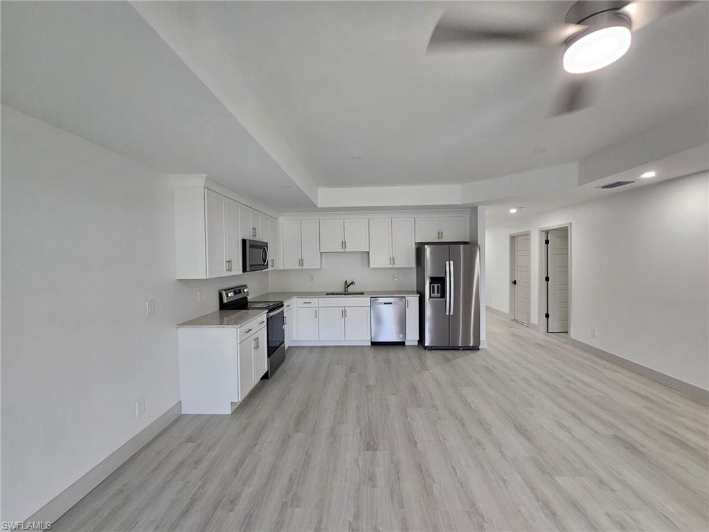 Kitchen with stainless steel appliances, white cabinetry, light wood-style floors, recessed lighting, and a raised ceiling