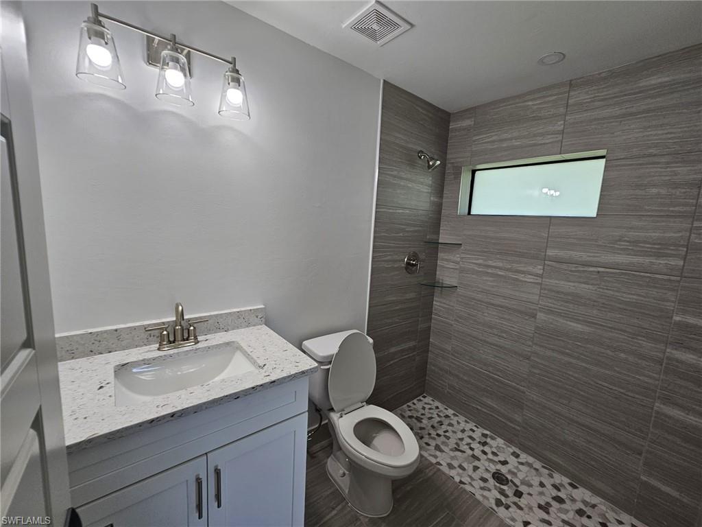Full bath with vanity, a shower stall, and dark wood-type flooring