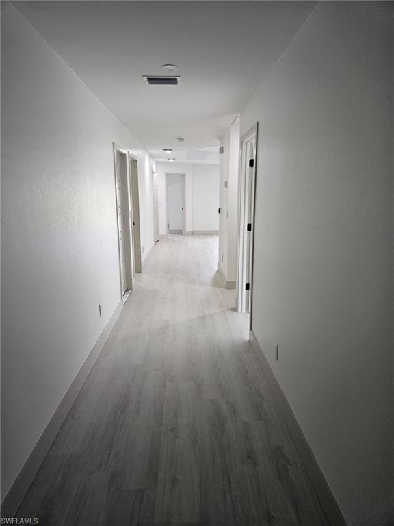 Hallway featuring light wood-type flooring and baseboards