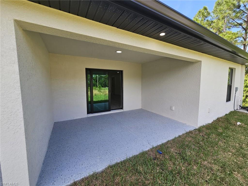 Doorway to property featuring stucco siding and a patio area