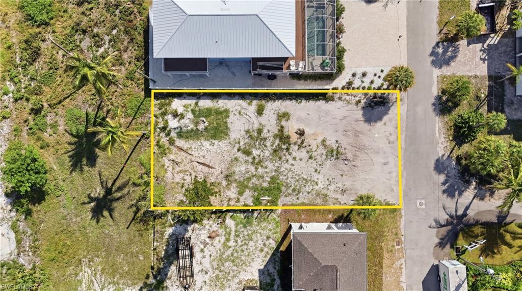 Cleared lot with surrounding mature palm trees and established neighborhood infrastructure. virtually enhanced