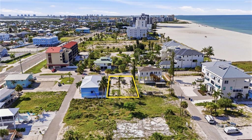 Cleared lot with existing palm trees, positioned between developed residential structures and a paved road. virtually enhanced