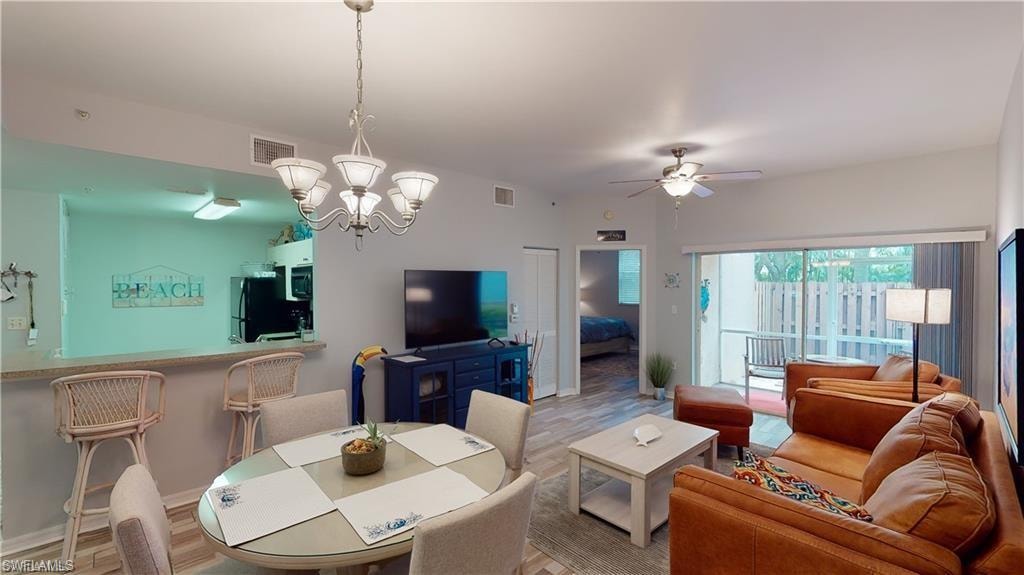 Living area with wood finished floors, a ceiling fan, and a chandelier