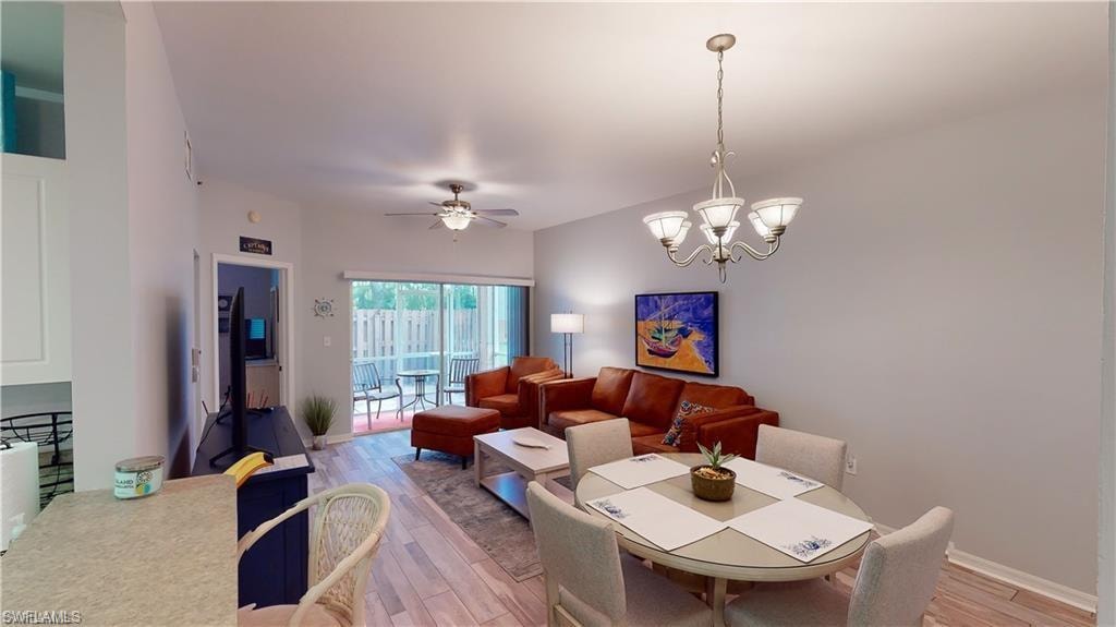 Dining area with light wood-style flooring, ceiling fan, and a chandelier