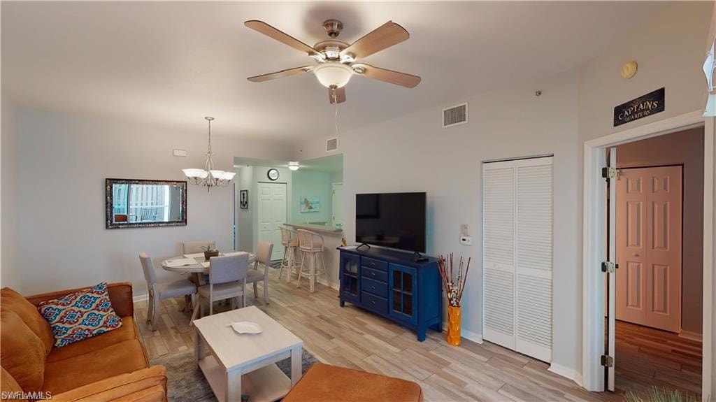 Living area with light wood finished floors, ceiling fan, and a chandelier