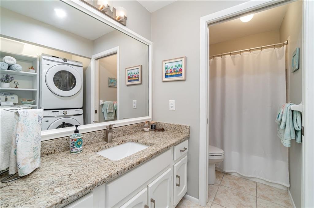Guest bathroom featuring granite counter, light tile floors, and slider door to toilet and shower/tub combo
