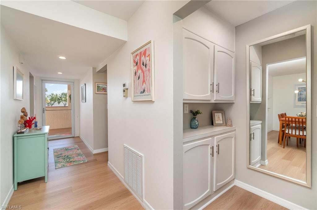 Hallway towards front door and primary bedroom with storage and recessed lighting