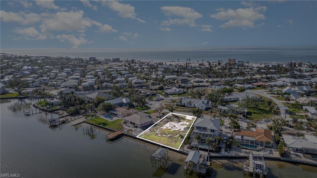 Aerial view of residential area featuring property parcel outlined and a nearby body of water