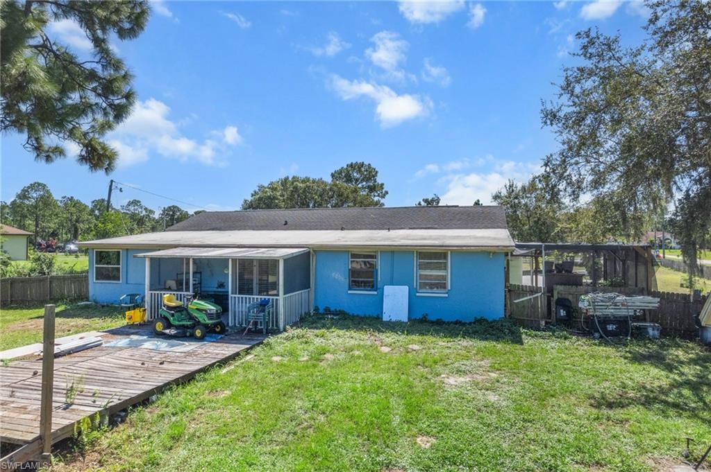 Back of house featuring a fenced backyard, a sunroom, stucco siding, and a deck