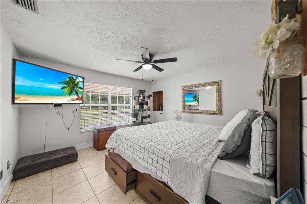 Bedroom featuring tile patterned floors, a textured ceiling, and ceiling fan