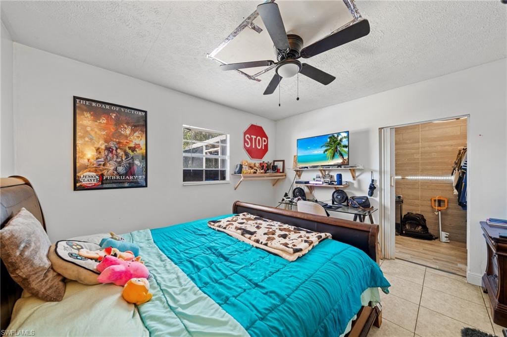Bedroom with a textured ceiling, tile patterned flooring, and ceiling fan