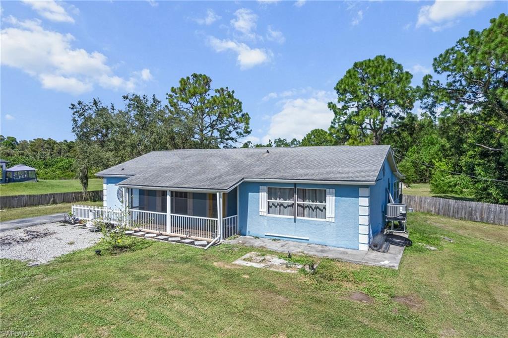 View of front of house featuring roof with shingles, stucco siding, and view of scattered trees