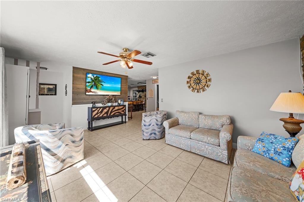 Living area with tile patterned flooring, a textured ceiling, and a ceiling fan