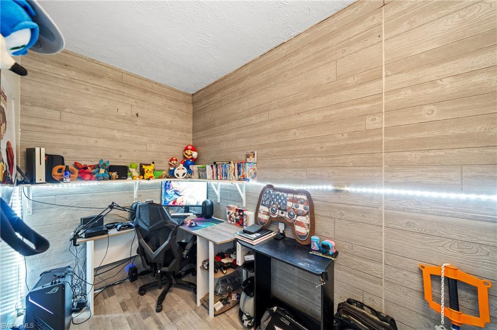 Office featuring wooden walls, wood finished floors, and a textured ceiling