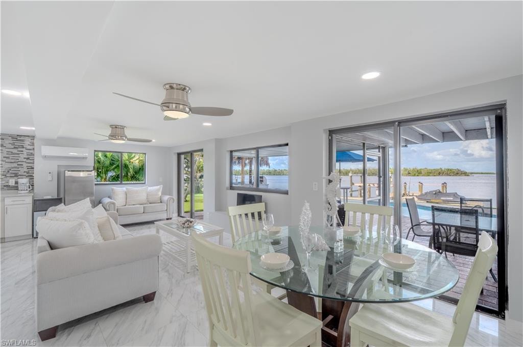 Dining room with light tile finish flooring, a water view, recessed lighting, a ceiling fan, and a wall unit AC - Virtually Edited Image