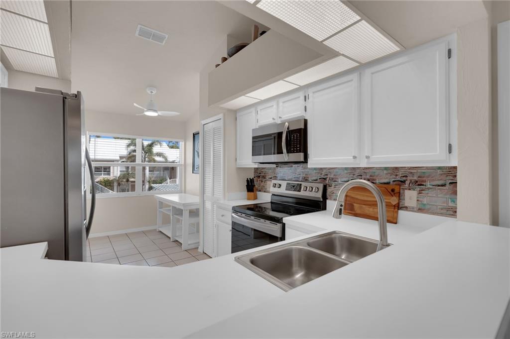 Kitchen with white cabinets, appliances with stainless steel finishes, light countertops, and tasteful backsplash