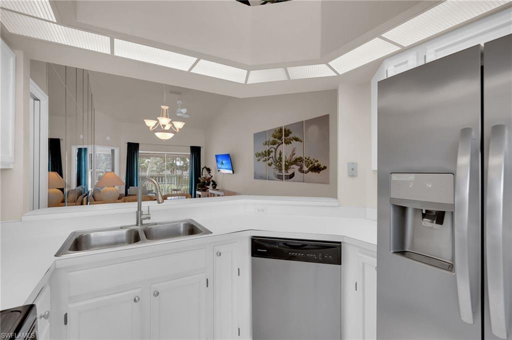 Kitchen featuring appliances with stainless steel finishes, white cabinetry, light countertops, and a chandelier