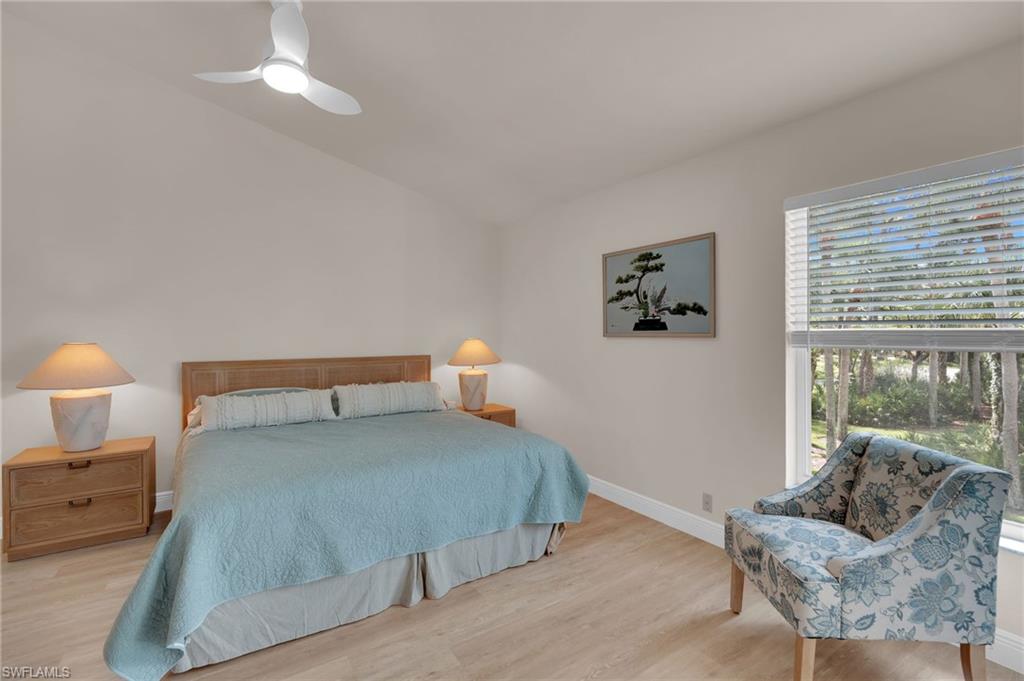 Primary bedroom with wood finished floors, a ceiling fan, and lofted ceiling