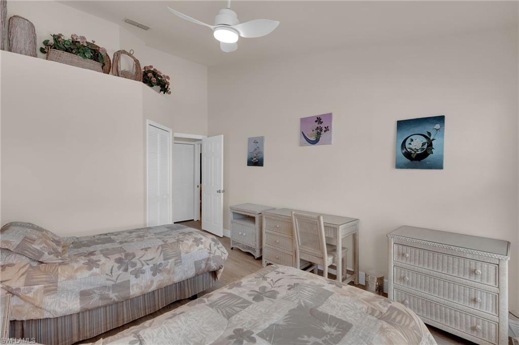 Bedroom with wood finished floors, a ceiling fan, a high ceiling, and a closet
