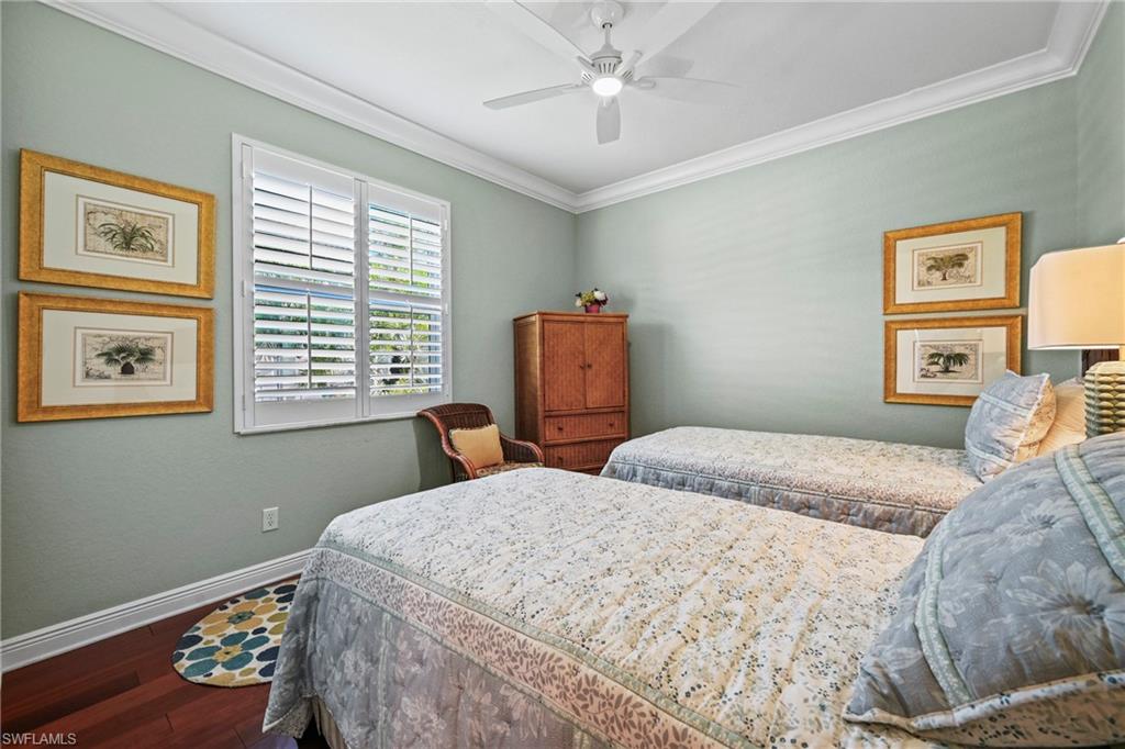 Bedroom featuring ornamental molding, dark wood-style flooring, and a ceiling fan