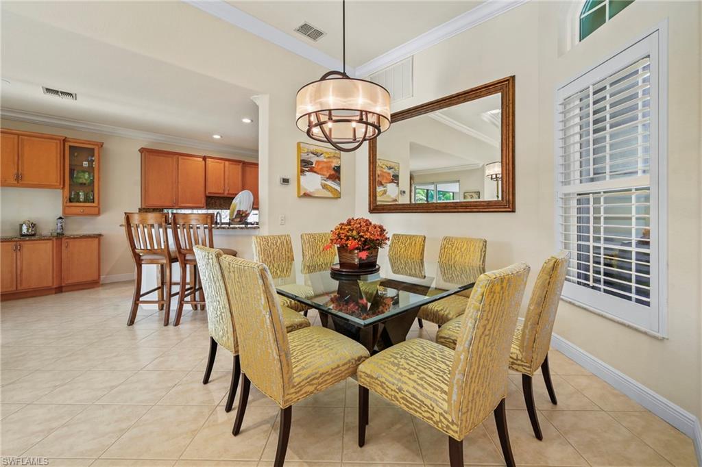 Dining room with light tile patterned floors, ornamental molding, a chandelier, and recessed lighting