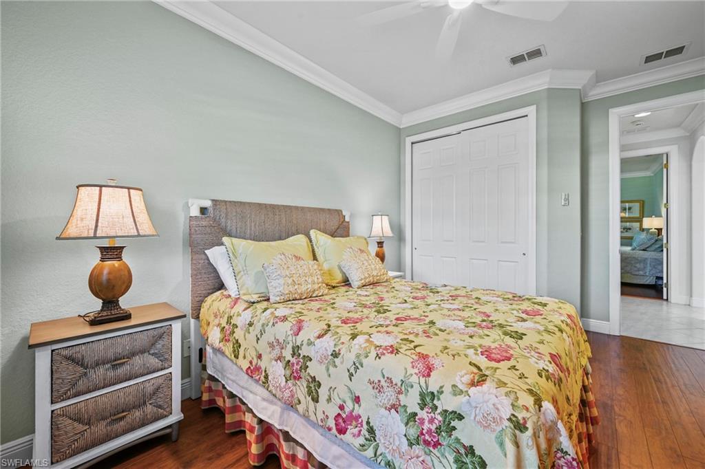 Bedroom with dark wood finished floors, ornamental molding, a closet, and a ceiling fan