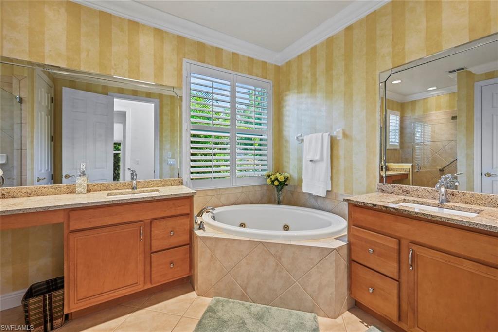 Full bathroom featuring plenty of natural light, wallpapered walls, ornamental molding, two vanities, and a whirlpool tub