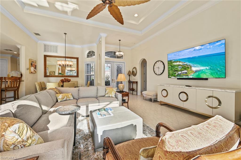 Living room with crown molding, ceiling fan, recessed lighting, arched walkways, and tile patterned flooring