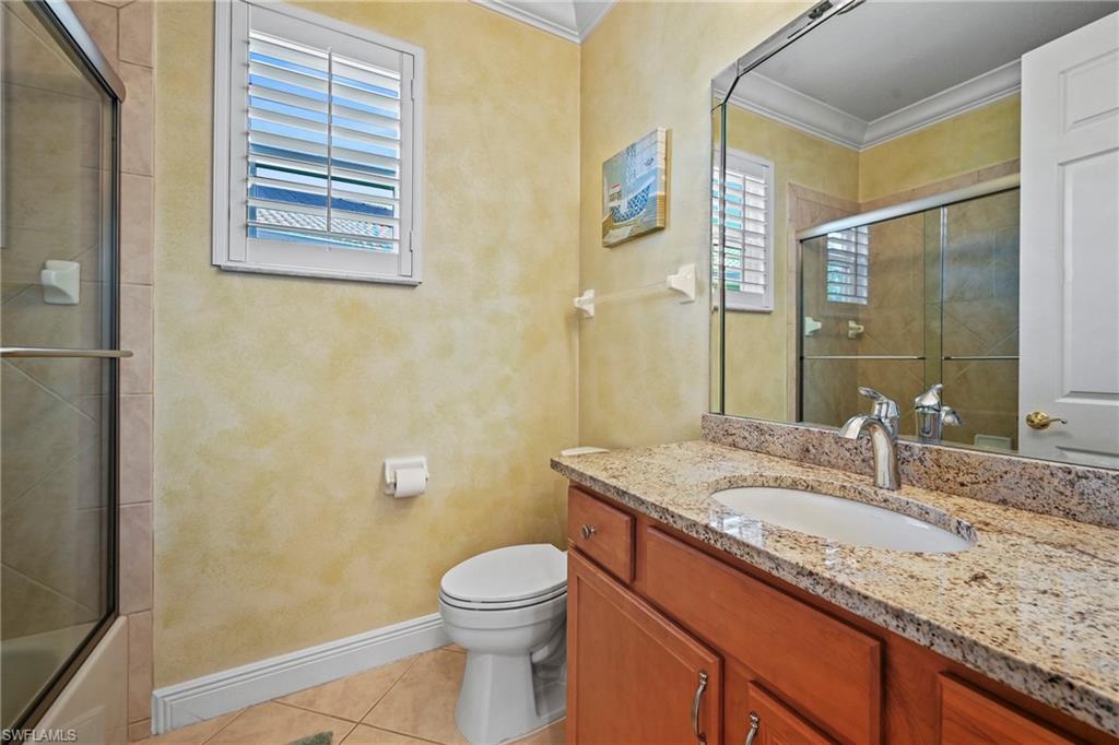 Full bath featuring light tile patterned floors, vanity, crown molding, and tiled shower / bath combo