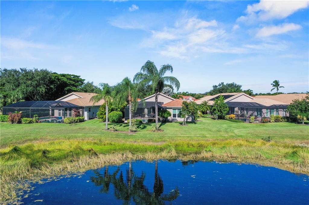 Rear view of house featuring a water view, a sunroom, a lawn, and glass enclosure