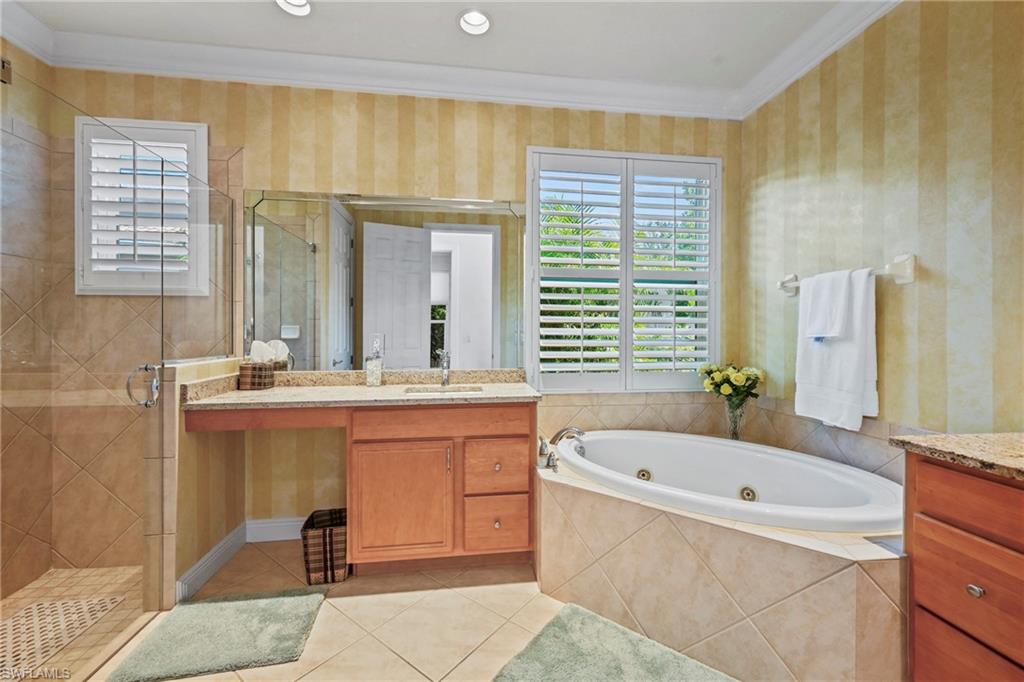 Bathroom with crown molding, healthy amount of natural light, vanity, a whirlpool tub, and wallpapered walls