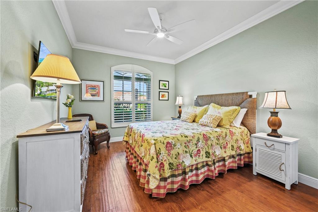 Bedroom with crown molding, wood finished floors, a textured wall, and a ceiling fan